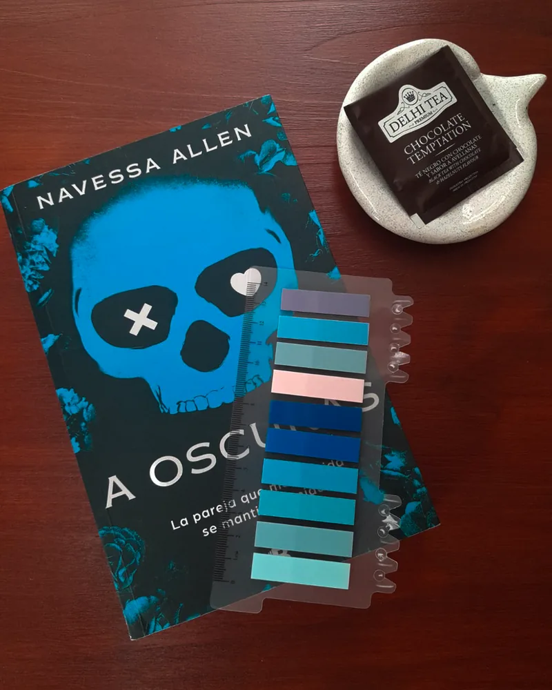 El libro A Oscuras, de Navessa Allen, con banderitas de colores, un saquito de té y un plato de cerámica