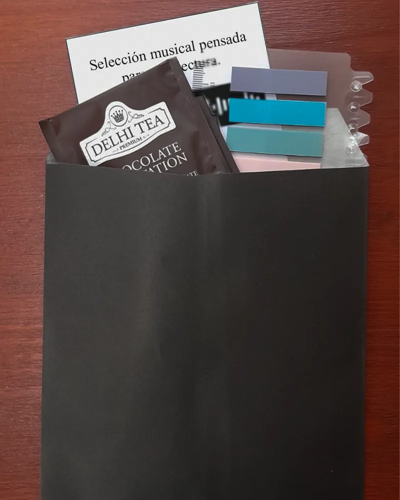 El sobre «Para antes de comenzar» con un saquito de té, una tarjeta con selección musical y banderitas de colores